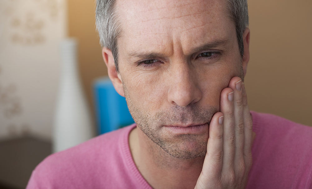 Man holds cheek with toothache - Las Vegas, NV